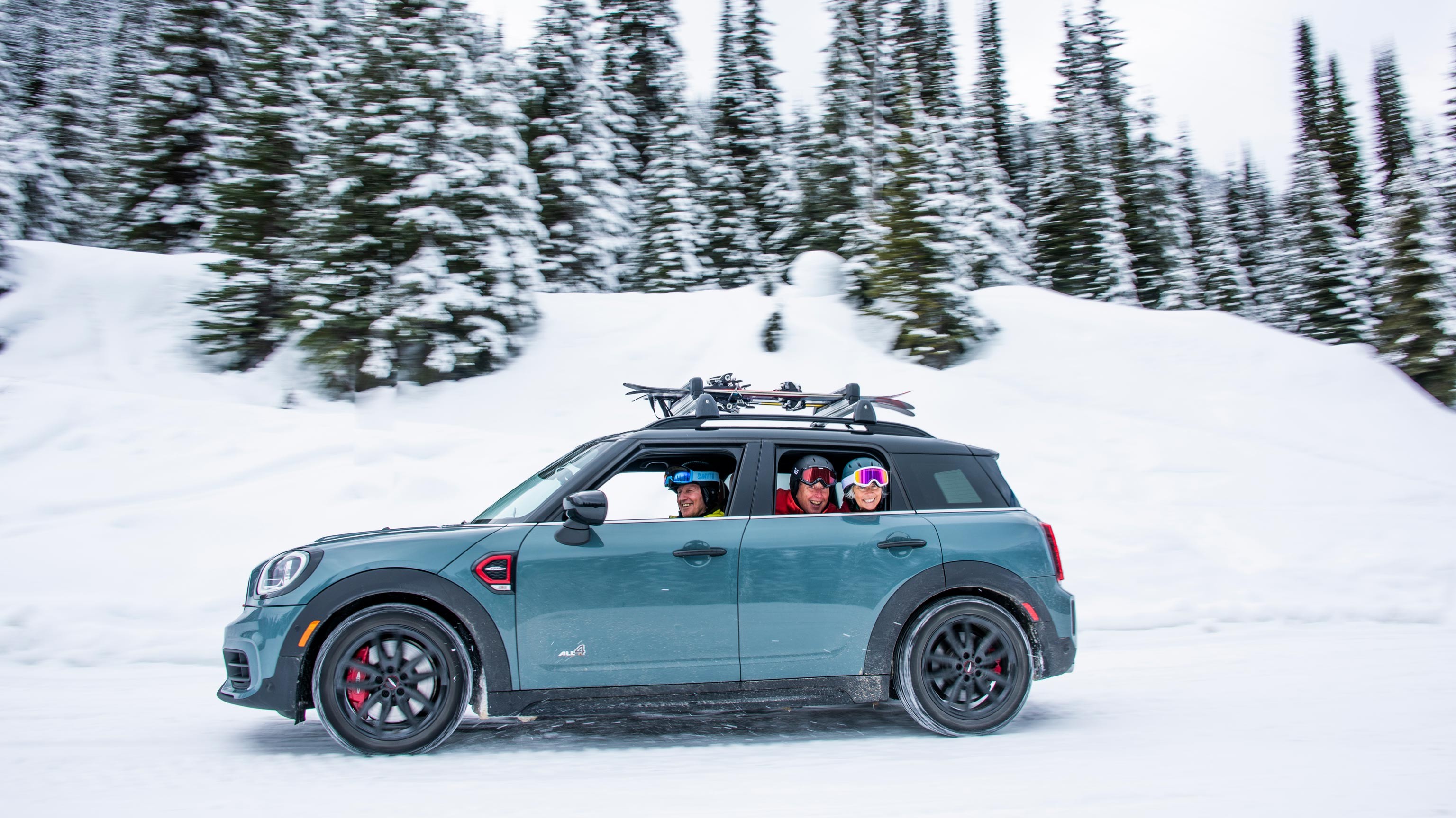 Image of a MINI Countryman in a snowy landscape, with members of a skiing group looking out of the window.
